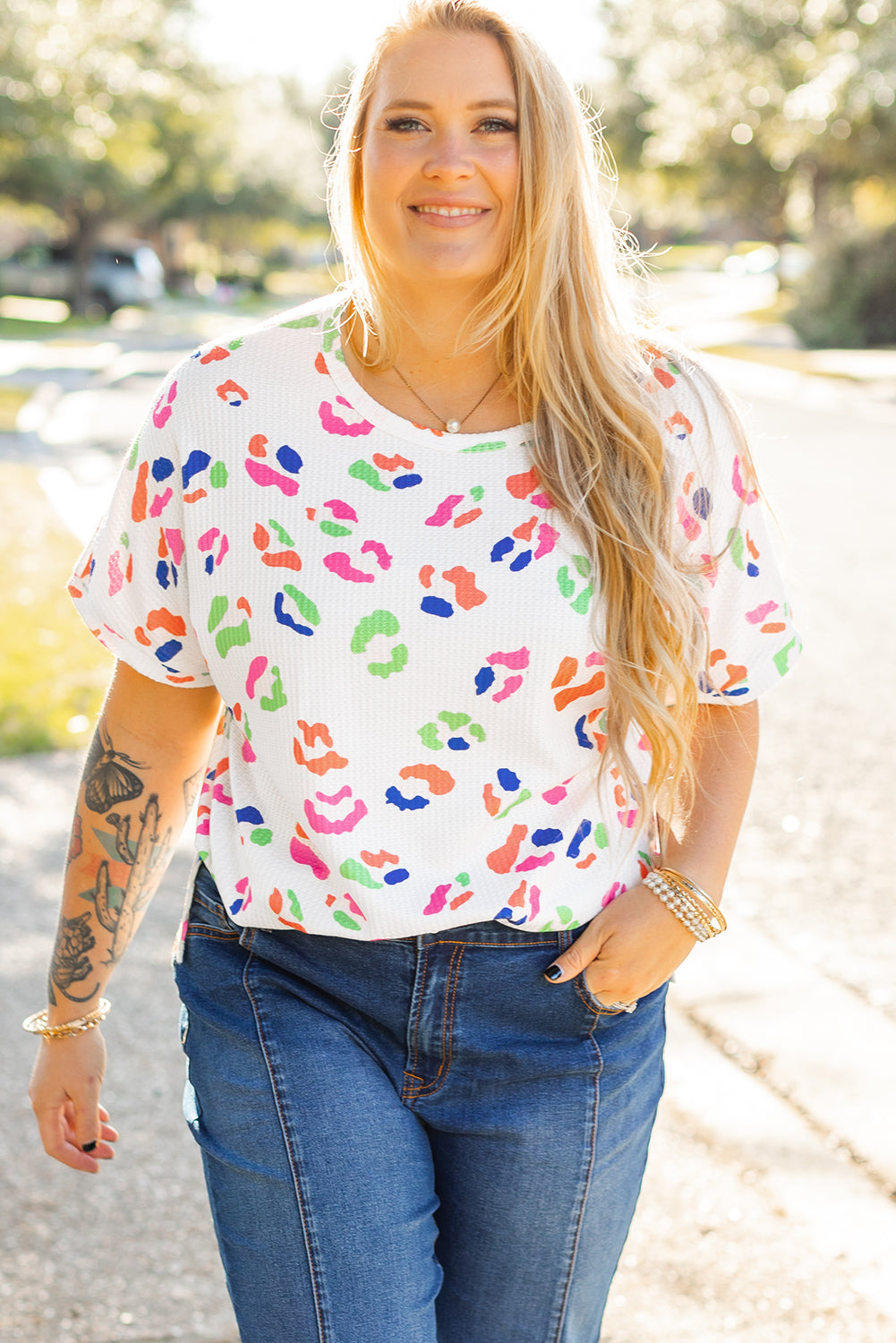 Plus size woman wearing white multicolor leopard top for women paired with blue jeans outdoor
