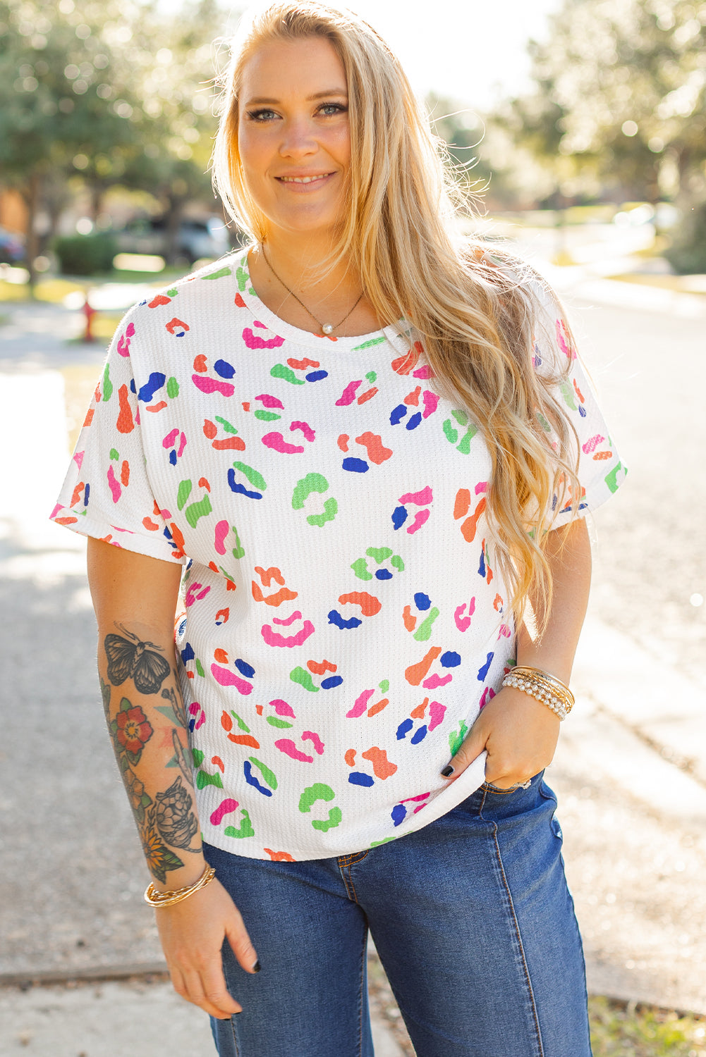 Plus size woman wearing a white multicolor leopard top for women with short sleeves outdoors