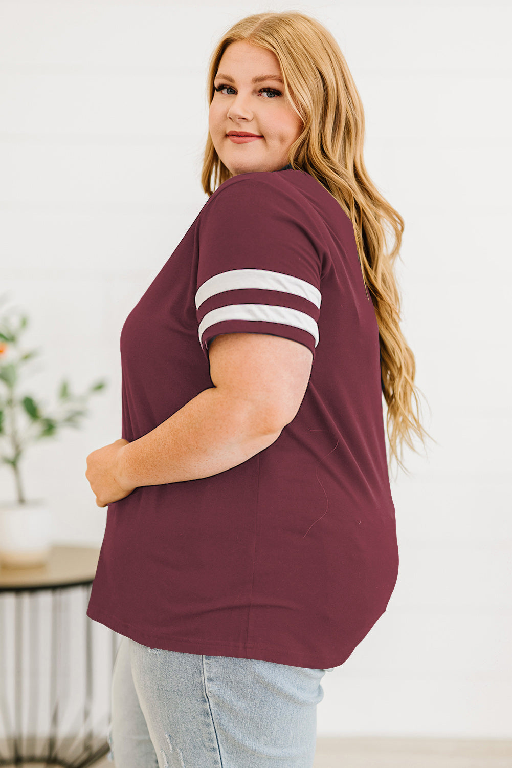 Women’s plus size striped sleeve top in burgundy with white stripes on sleeves worn with light wash jeans