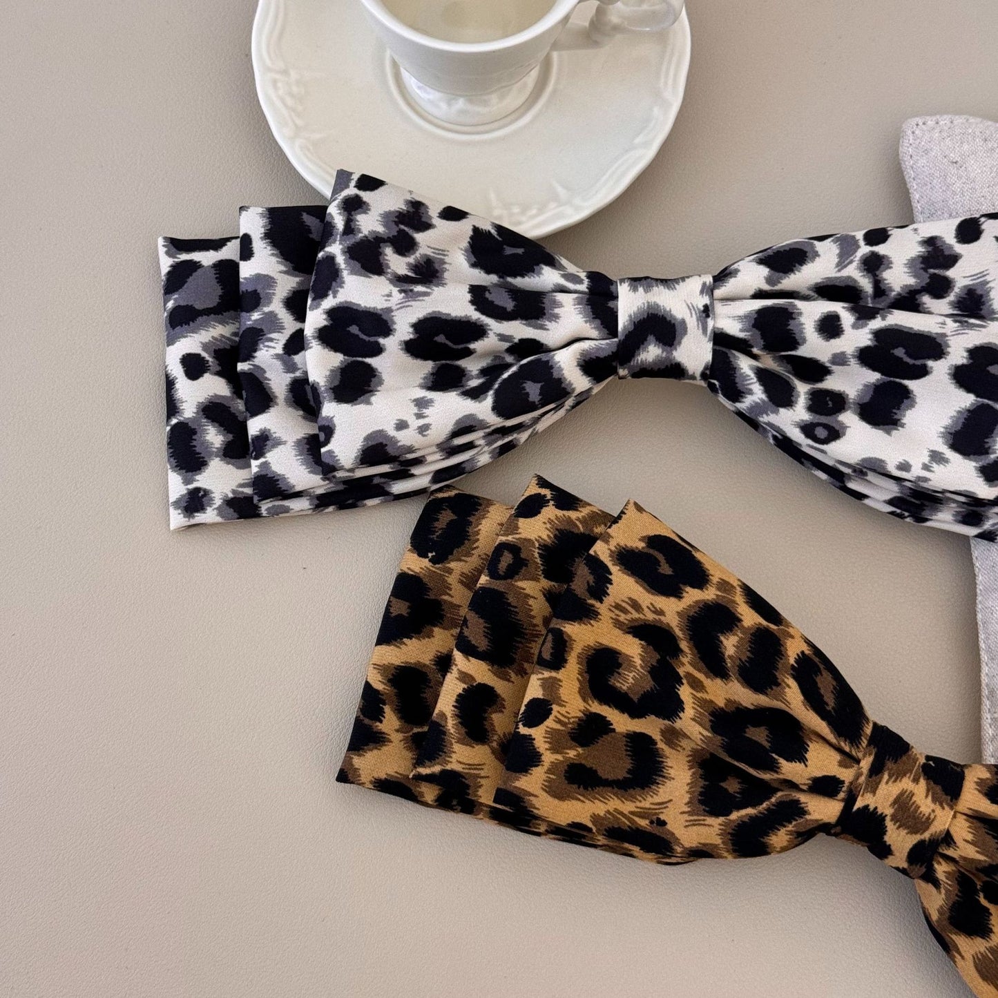 Two piece leopard print hair clips in white and brown with black spots by Trendsi on beige background