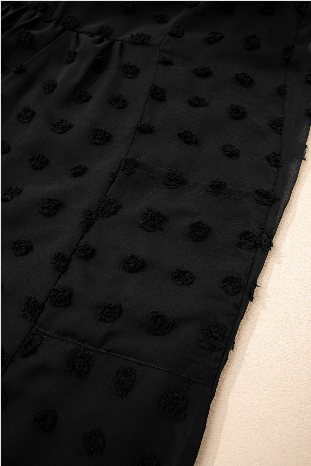 Close-up of black dotty plus size summer dress fabric with textured polka dot pattern