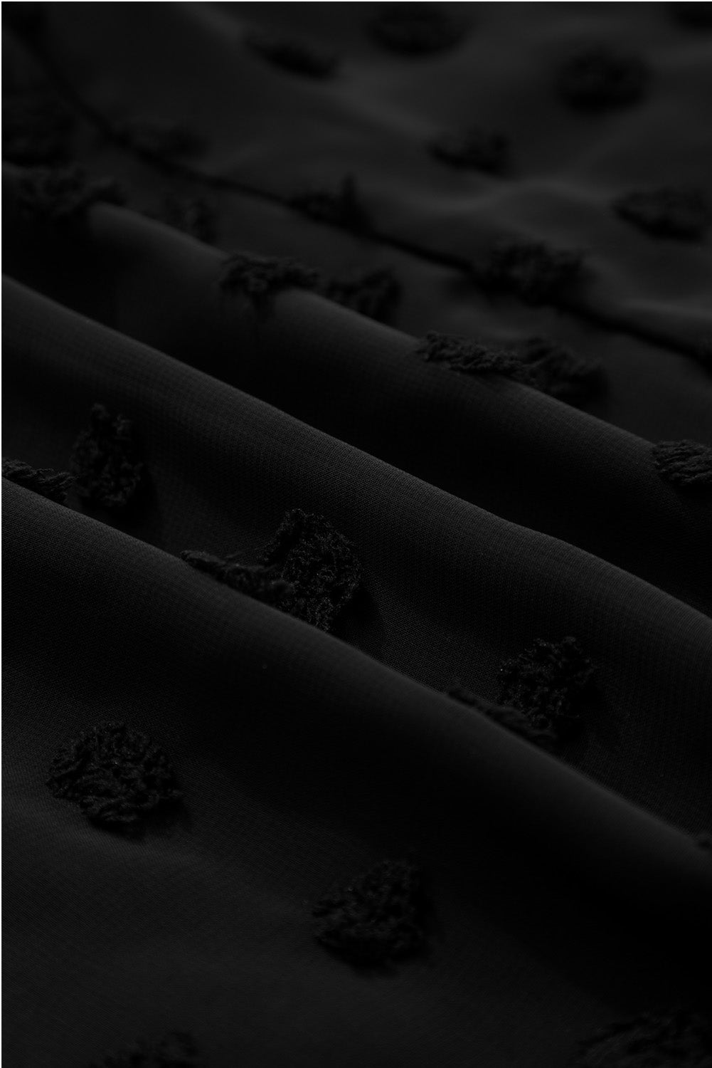 Close-up of fabric texture on black dotty plus size summer dress showing raised dot pattern