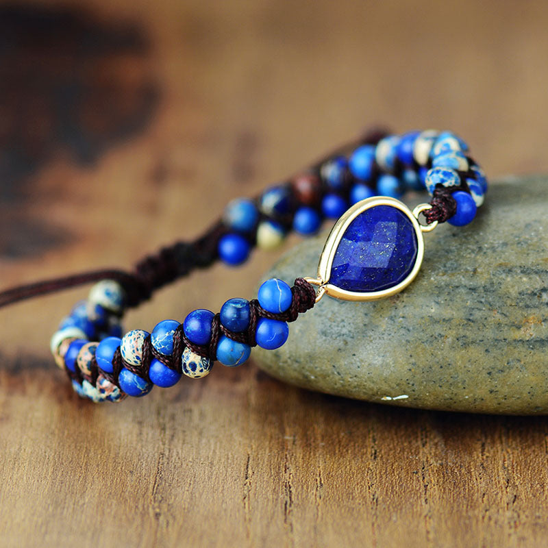 Trendsi blue gemstone teardrop bracelet with natural blue beads and gold-tone setting on wooden surface