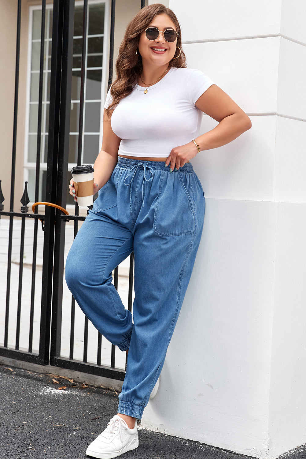 Plus size model wearing drawstring waist plus size jeans in blue with casual white top and sneakers