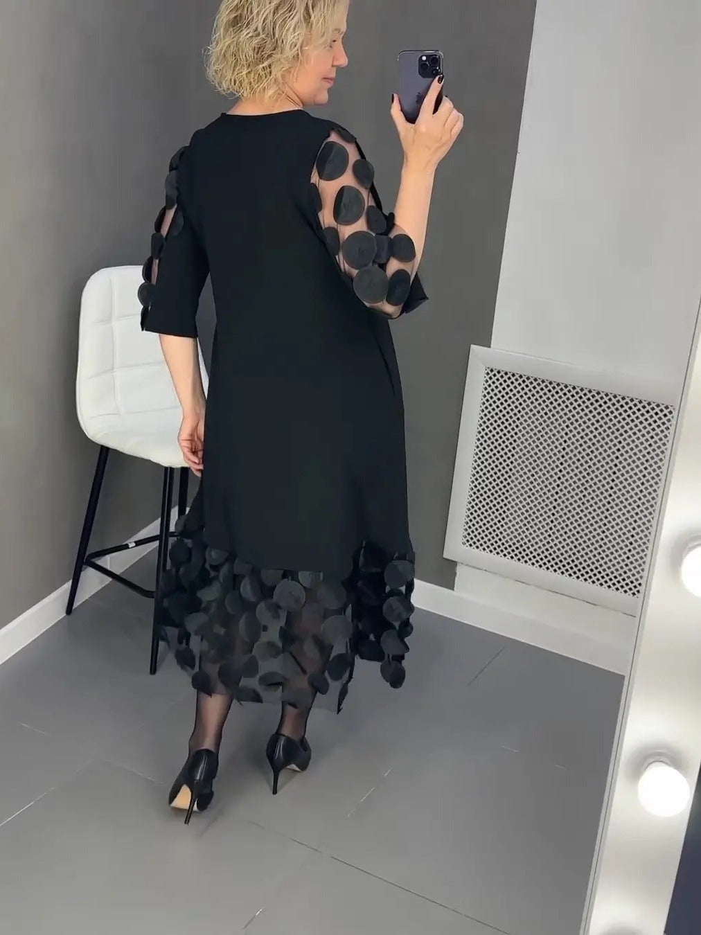 Elegant black dress for curvy women with sheer polka dot sleeves and hem modeling back view