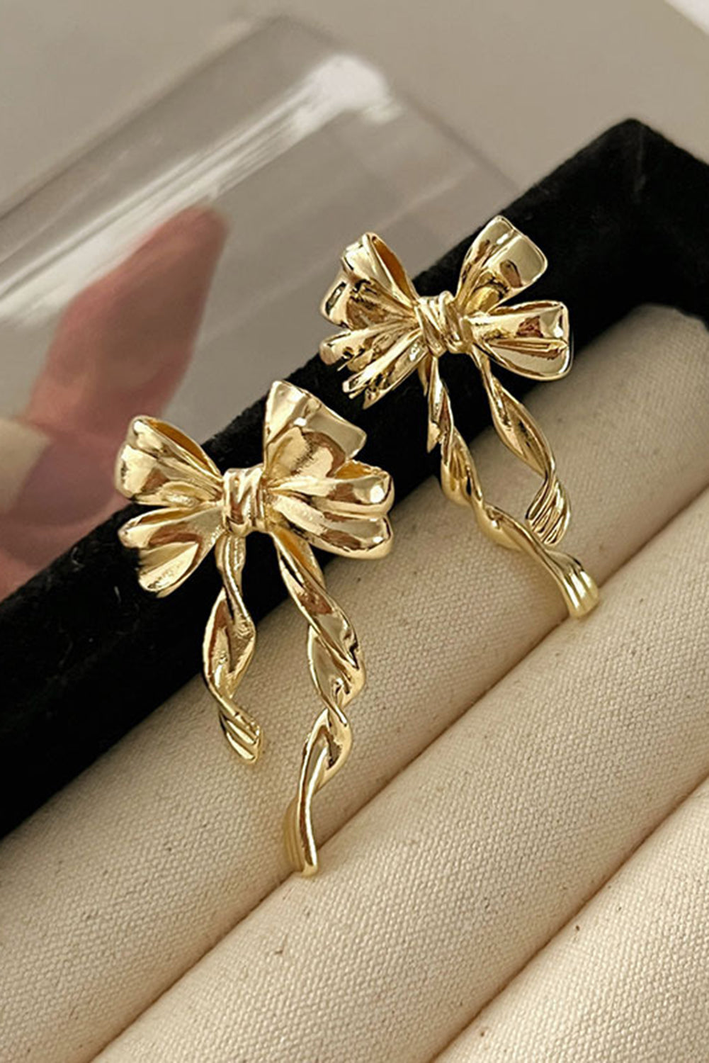 Gold bow stud earrings with elegant twisted ribbon design by kjplussizefashion displayed on fabric