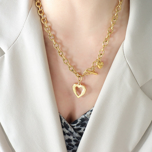 Gold chunky titanium steel heart necklace with heart-shaped pendant worn with beige blazer
