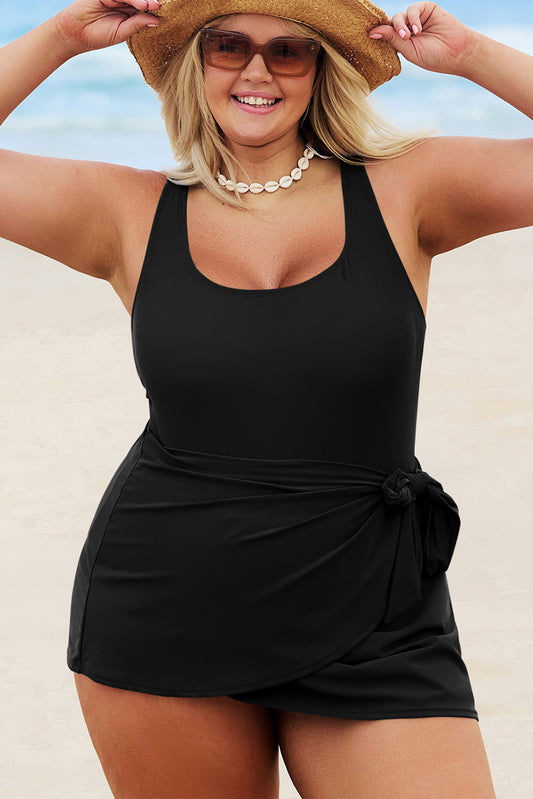 Plus size black one piece swimsuit with skirted bottom and side tie detail worn at the beach