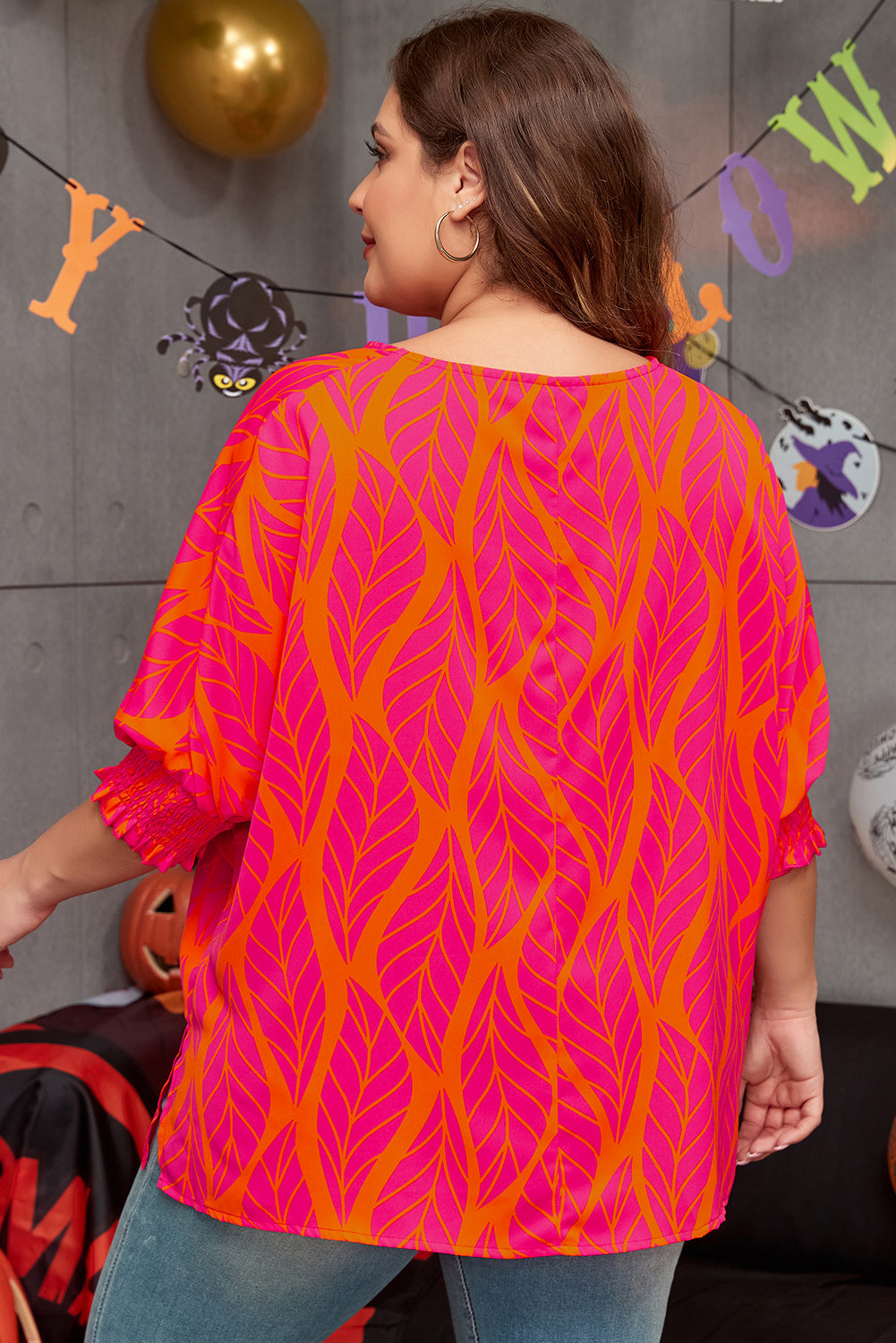 Back view of plus size rose print blouse with pink and orange leaf design on model