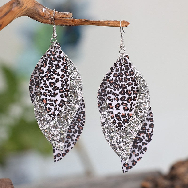 Trendsi PU leather statement earrings with leopard print and silver glitter layered design hanging on wooden branch