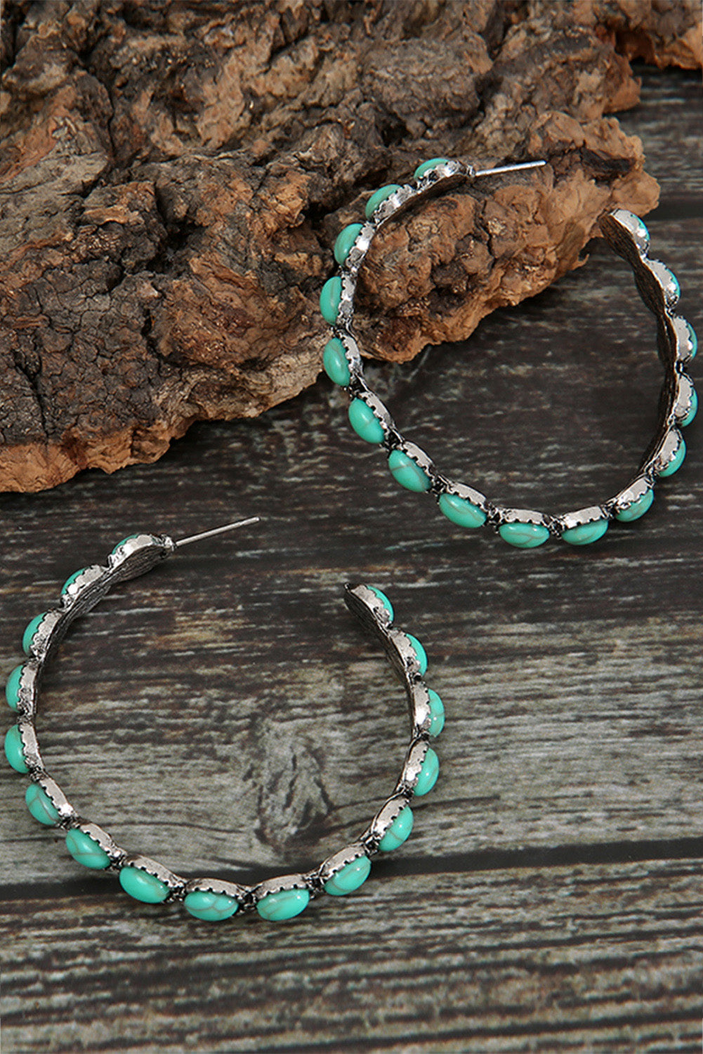 Sky blue gem hoop earrings with silver settings displayed on rustic wooden surface