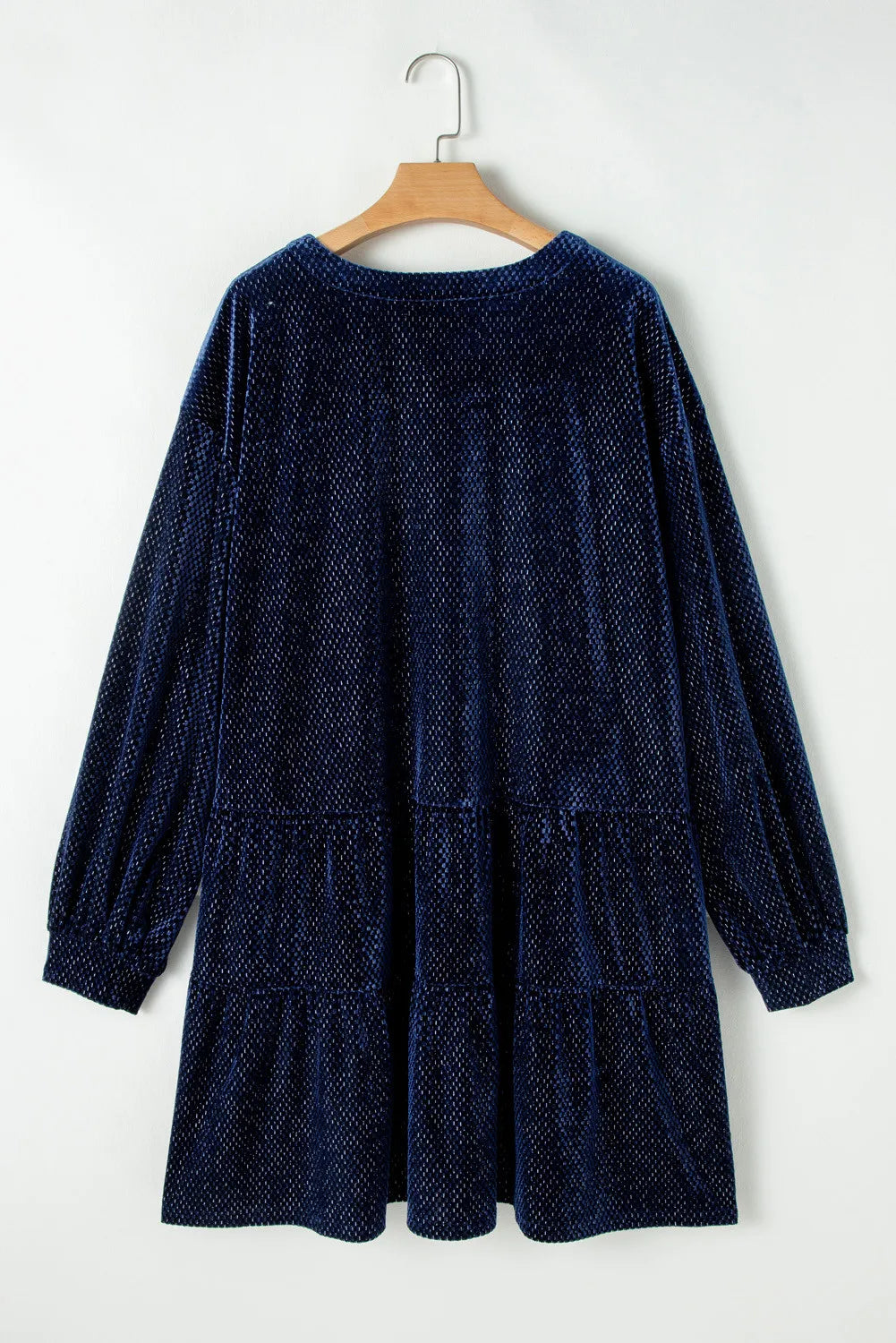 Navy blue textured velvet dress for curvy women with long sleeves hanging on wooden hanger