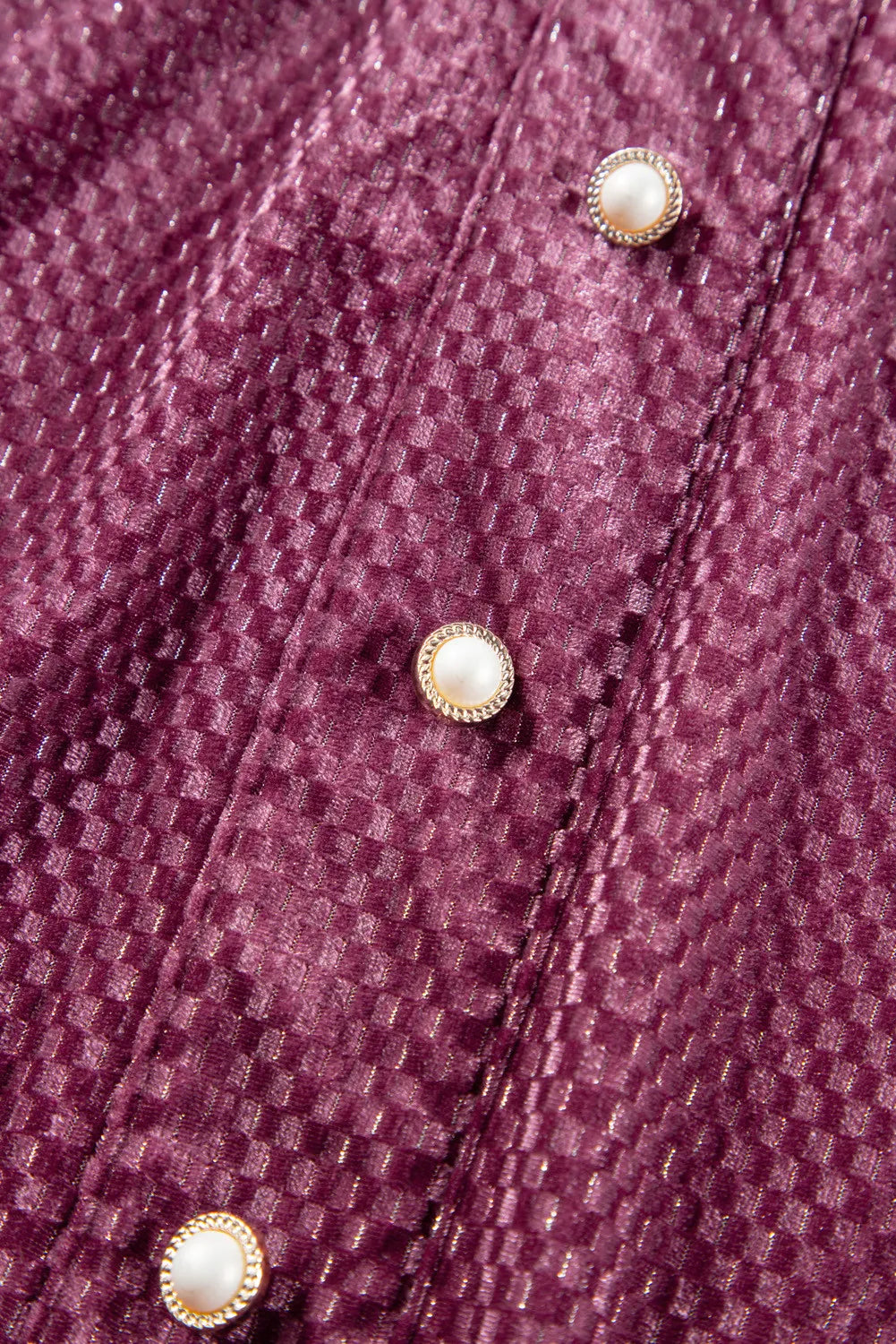 Close-up of textured velvet dress for curvy women in deep purple with decorative pearl buttons