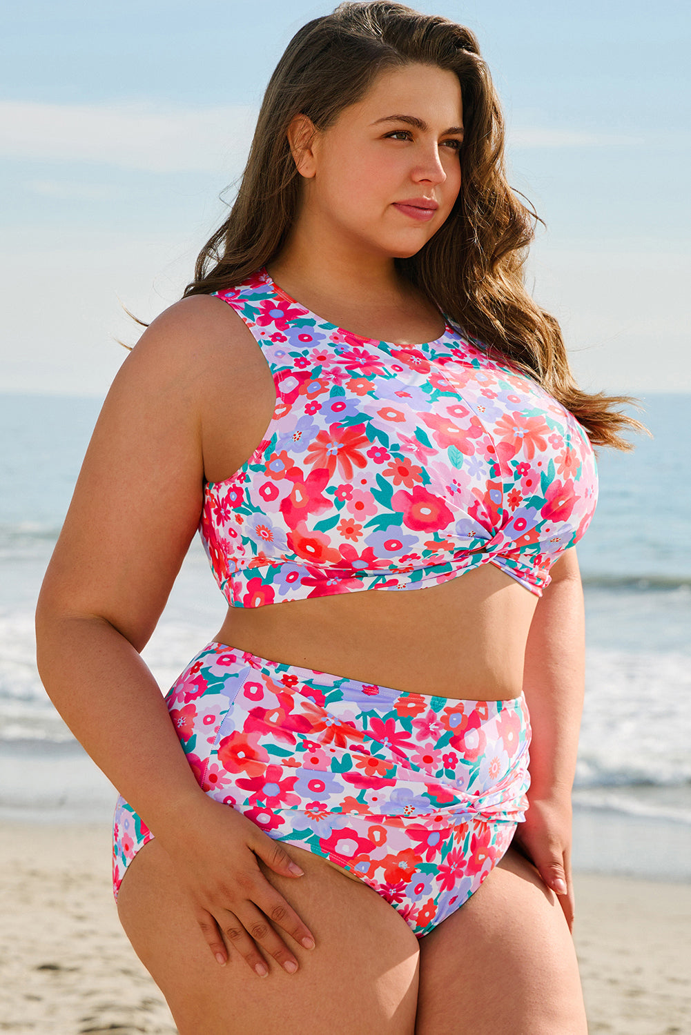 Plus size model wearing a colorful floral twisted high waist bikini for curvy women on the beach