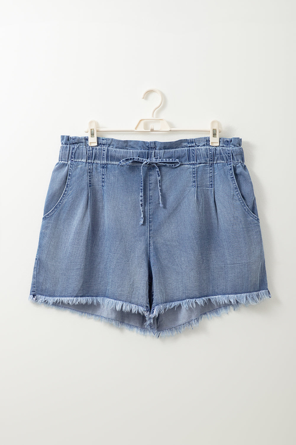 Comfortable plus size summer shorts in light denim with drawstring waist and frayed hem