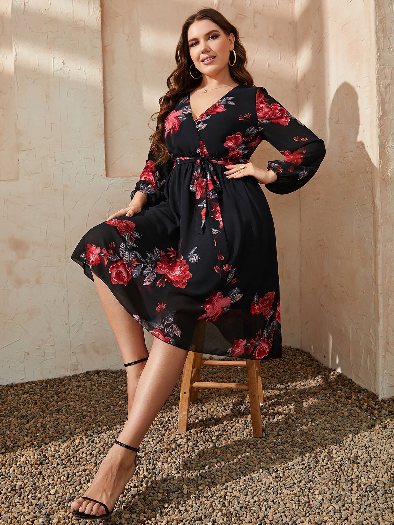 Trendsi plus size floral dress in black with red rose print and long sleeves styled on a seated woman