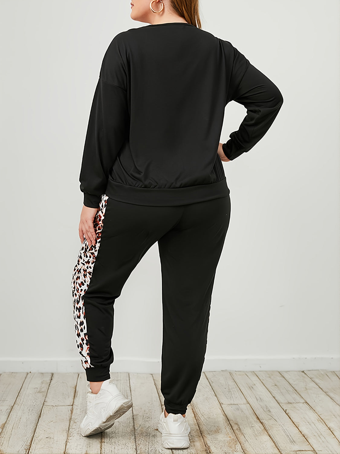 Back view of plus size leopard print tracksuit with black long sleeve top and leopard print side stripe pants