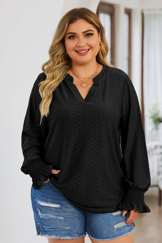 Plus size trendy blouse for women in black with long sleeves and smocked cuffs paired with distressed denim shorts
