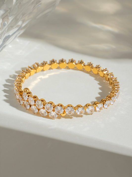 Gold stainless steel zircon bracelet with sparkling round stones on a light surface
